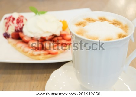 Cappuccino coffee cup and vanilla  ice cream with strawberry and whipp cream in background