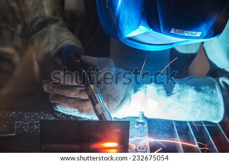 close up of worker with protective mask welding metal