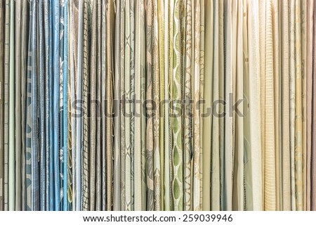 Colorful curtain samples hanging from hangers on a rail in a display in a retail store