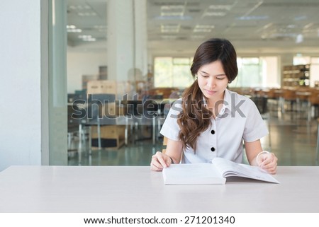 Asian student in uniform reading book at classroom