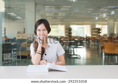Asian student in uniform reading book at classroom