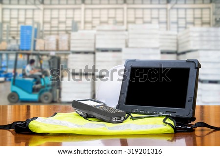 Rugged computers tablet and Bluetooth barcode scanner in front of modern warehouse