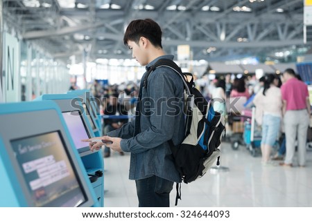 Young Asian man using self check-in kiosks in airport.(color toned image)