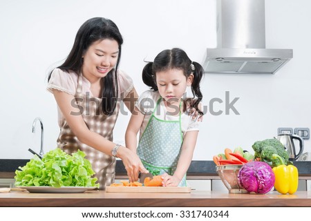 family, children and happy people concept - Asian mother and kid daughter cooking in the kitchen at home