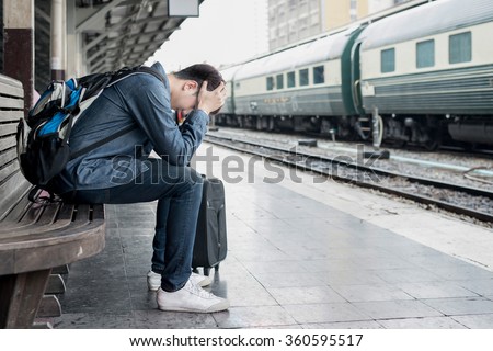 Travel by train - Asian depressed traveler waiting at train station after mistakes a train. Asian traveler looking anxiety at train station