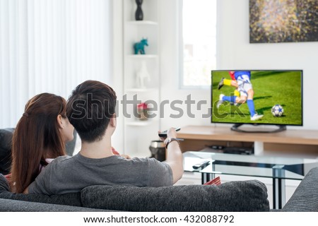 Sport, football, People concept - Young Asian couple watching football sport on tv at home. Asian couple looking enjoy football sport game.Euro football match