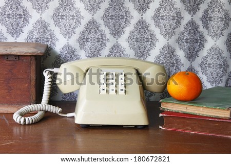 still life with old book,Push Button Telephone and orange on wooden table.