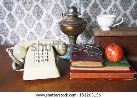 still life with old book,glasses,Push Button Telephone,lamp,tea cup and apple on wooden table.