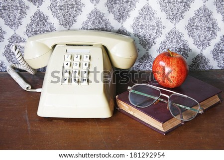 still life with old book,glasses,Push Button Telephone and apple on wooden table.
