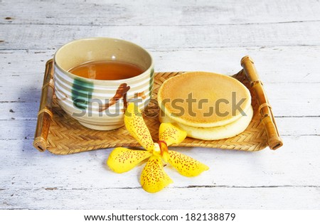 Dorayaki Japanese Traditional Pancake Dessert with cup of tea in bamboo tray on wooden table.