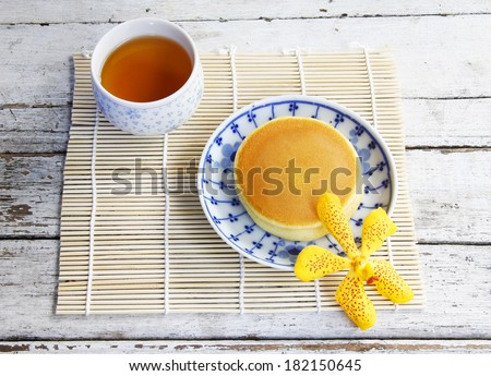 Dorayaki Japanese Traditional Pancake Dessert with cup of tea in bamboo tray on bamboo map.