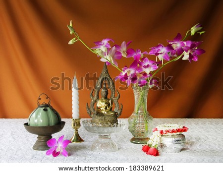 still life with candle,vase,orchid,silver bowl,glass tray with pedestal,brass tray with pedestal,jasmine garland,buddha statue and Porcelain lamp. songkran festival thailand new year.