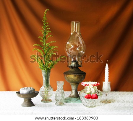 still life with lamp,candle,vase,silver bowl,glass bowl,glass tray with pedestal,brass tray with pedestal,jasmine garland.