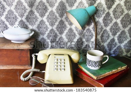 still life with old book,Push Button Telephone,glasses,lamp and tea cop on wooden table.