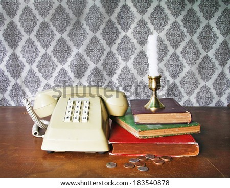 still life with old book,Push Button Telephone,candle and coins on wooden table.