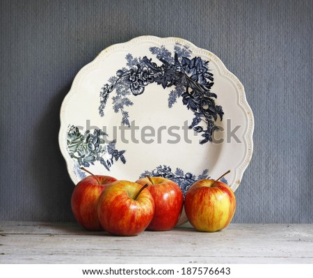 still life with blue and white porcelain dish ware and red apples on wooden table.