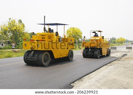 LOP BURI,THAILAND - APRIL 10 :Workers operating asphalt paver machine and heavy machinery during repairs road under the program repairs highway road on April 10,2014 in Lop Buri,Thailand.