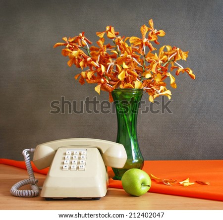 still life with Push Button Telephone,vase of orchid and apple on wooden table.