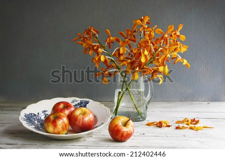 still life with blue and white porcelain dish ware,red apples and jug of orchid on wooden table.