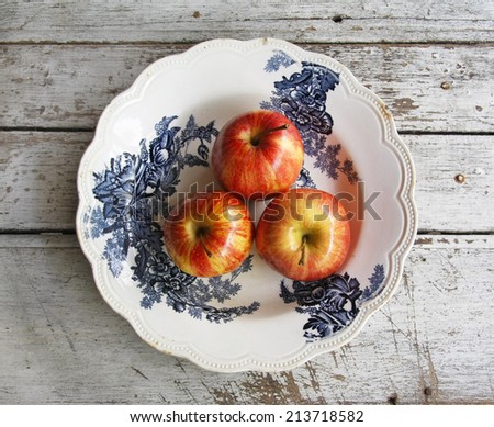 still life with blue and white porcelain dish ware and red apples on wooden table.