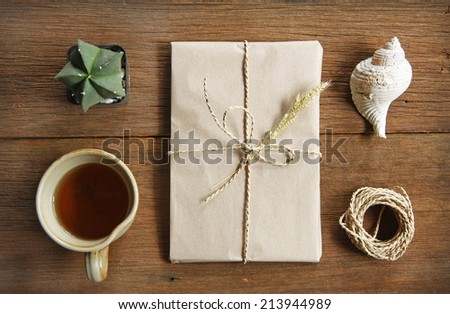 still life with postal parcel wrapped in brown paper and the contents of a workspace composed. Different objects on wooden table.