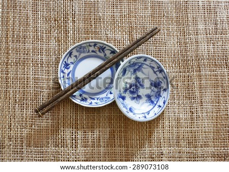 ceramic dish (plate) and chopsticks on bamboo mat.