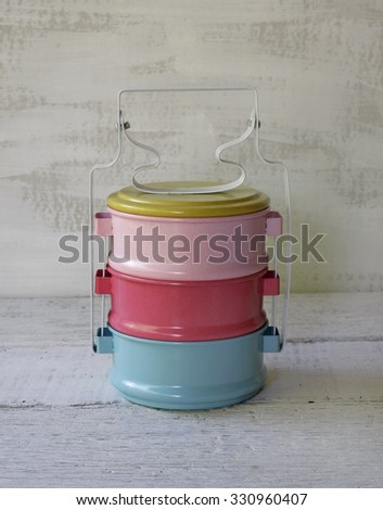 Still life with colorful retro food carrier on wood table background
