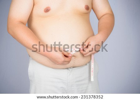 Fat mature man measuring his belly with measurement tape,