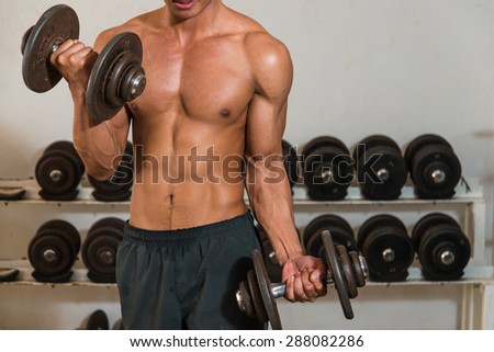 Very power athletic guy bodybuilder , execute exercise with dumbbells in gym