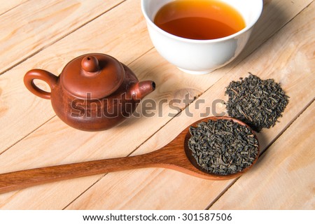 Teapot chinese style, Cup of chinese tea and spoon of dried tea leaves on wooden background