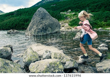 Side view of little girl jumping from stone to stone in the Tatra Mountains