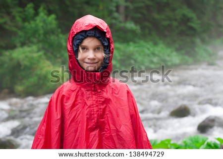 Little girl in raincoat.  Mountain stream in background