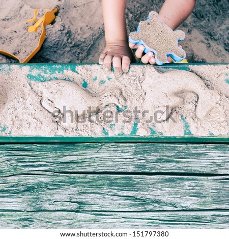 Kid creating animal forms in sandpit