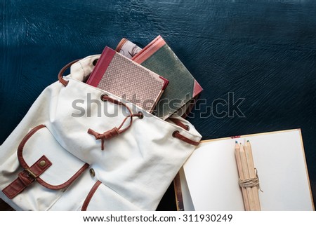 Notebooks pencils and school bag on a desktop