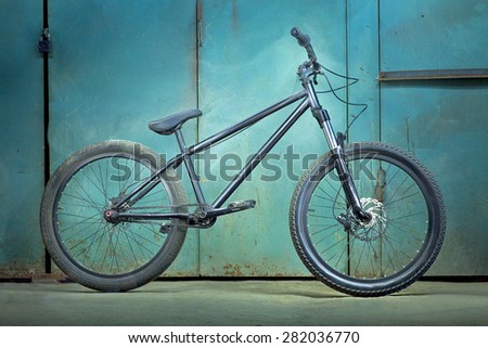 Black bicycle on a green garage background with light effects