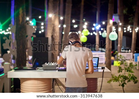 DJ at work in outdoor cafe, night photo.