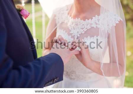 The bride wears a wedding ring on finger of the groom.