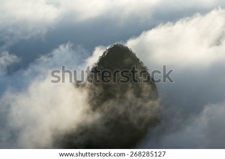 An isolated granite mountain peak in a sea of clouds during the blue hour of sunrise, Huangshan (Yellow Mountains), Anhui Province, China