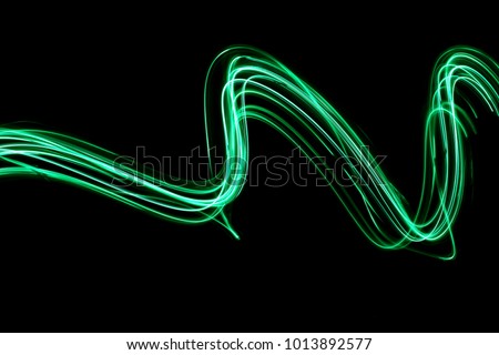 Green light painting photography - curves and waves of neon green light against a black background