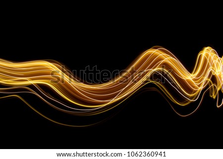 Gold light painting photography, long exposure photo of metallic fairy lights against a black background