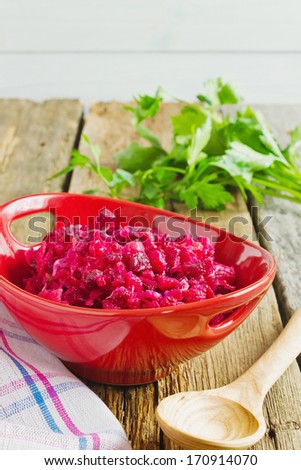 beetroot salad in a red bowl and parsley on the table