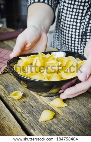hands holding a bowl of uncooked pasta