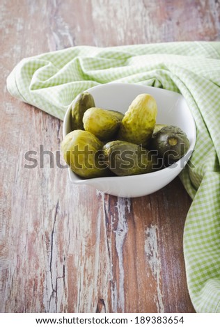 small pickles in white bowl on wooden background