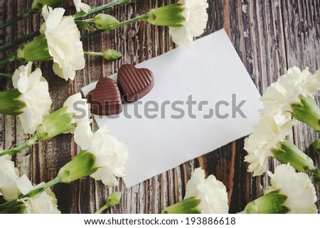 white carnations, chocolates and white sheet of paper. love letter