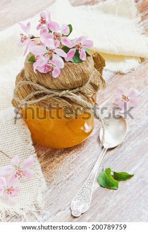 orange marmalade in a glass jar and orange flowers on the table