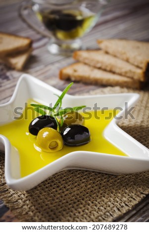 olive oil in a saucer, bread and olives on a wooden background.selective focus. health and diet concept