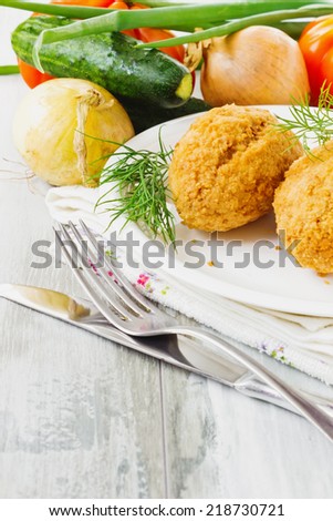 breaded cutlets on a plate and fresh vegetables on the table.  cutlets kievski
