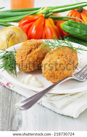breaded cutlets on a plate and fresh vegetables on the table.  cutlets kievski