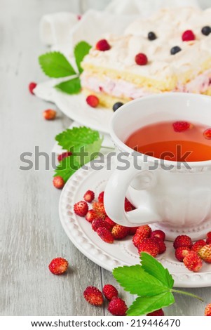 strawberry tea and a piece of cake with blueberries and strawberries on old wooden background. selective focus