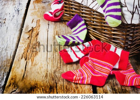 scattered children\'s striped socks and laundry basket on a wooden background. children\'s clothing.